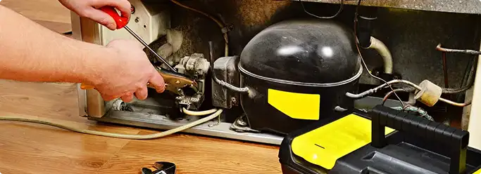 Refrigerator repair technician fixing the compressor and wiring in Lyons, CO