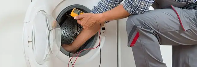 Dryer repair technician inspecting and repairing a clothes dryer in Boulder, CO