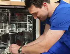 Dishwasher repair technician inspecting and servicing an open dishwasher in Boulder, CO