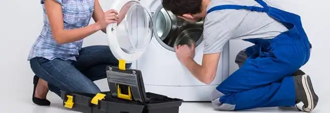 Washer repair technician inspecting a front-load washing machine with tools in Boulder, CO