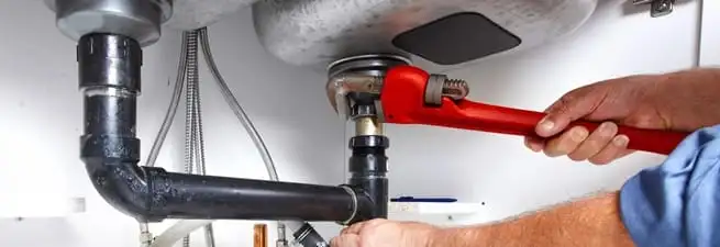 Garbage disposal repair technician tightening the sink drain and disposal connection in Boulder, CO