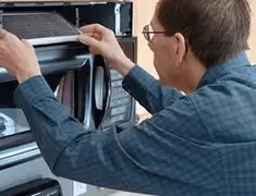 Appliance repair technician replacing a microwave vent filter in Boulder, CO