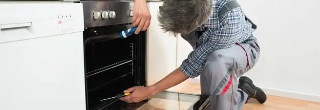 Oven repair technician inspecting and servicing an electric oven in Boulder, CO