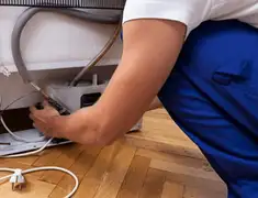 Appliance repair technician fixing refrigerator water line and connections in Boulder, CO