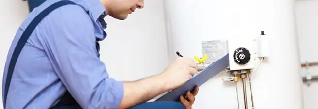 Water heater repair technician inspecting the unit and recording service notes in Boulder, CO