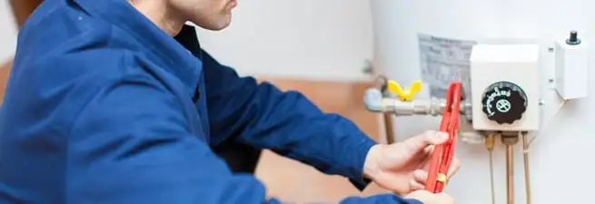 Water heater repair technician adjusting the temperature control and gas valve in Boulder, CO